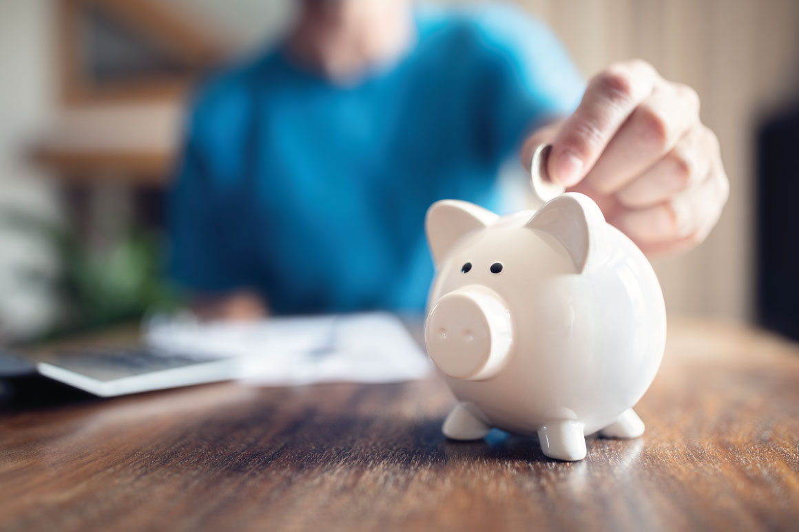 Person putting coin into the piggy bank. 
