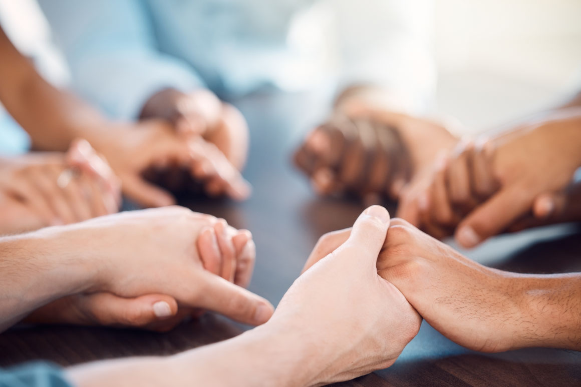 People holding hand at a table to study their faith