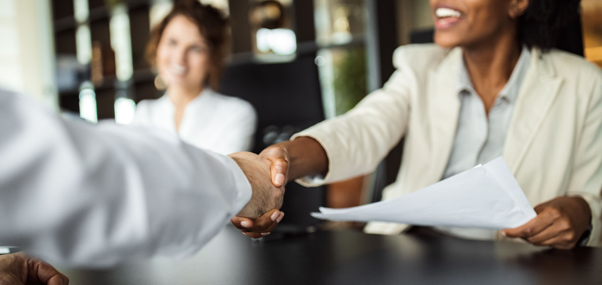 Business woman shaking someone's hand over the table