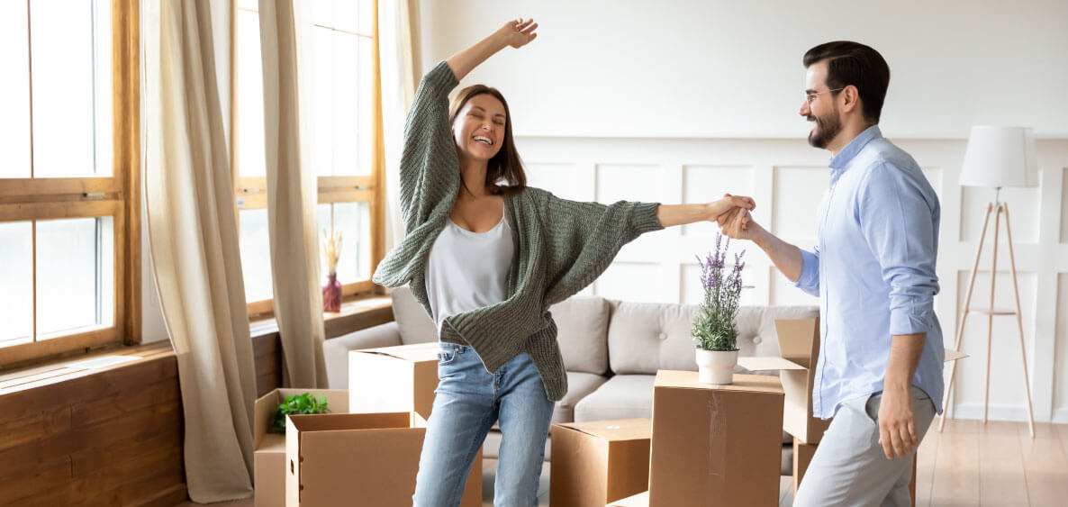 Happy woman dancing with hands in the air while man holds her hand