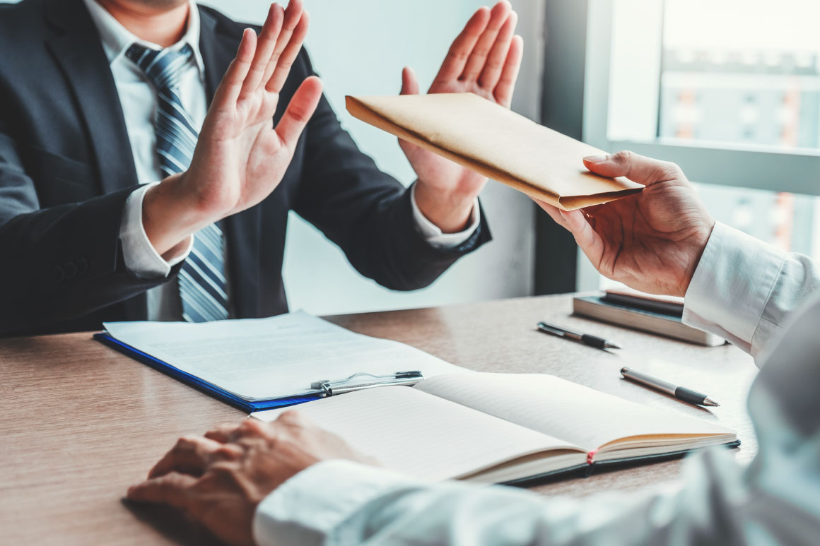 One business person handing the other one a brochure but the other one has his or her hand up in rejection.