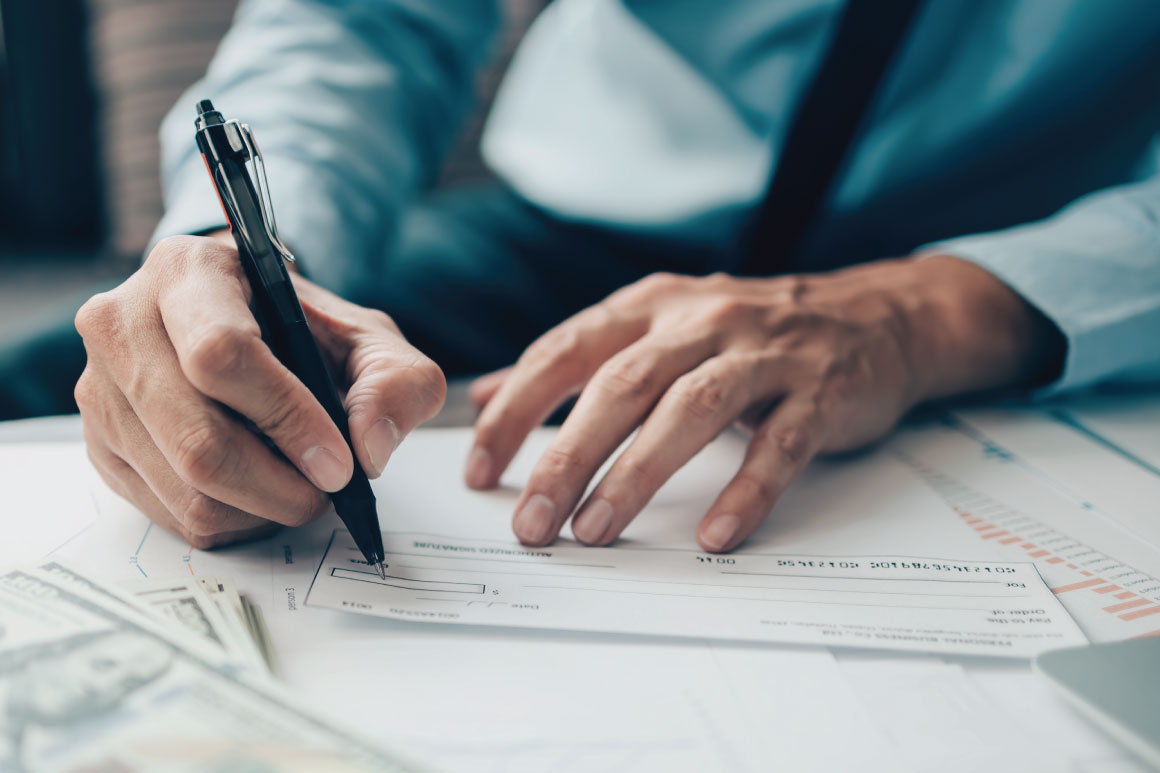 Hands with a pen writing a check