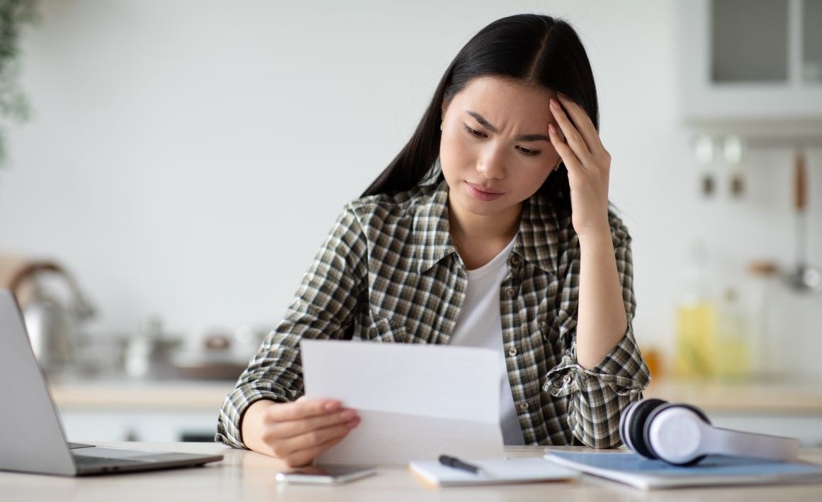 Woman looking at a statement with a concern look on her face.