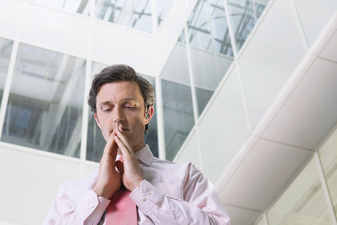 Man in pink dress shirt and tie praying