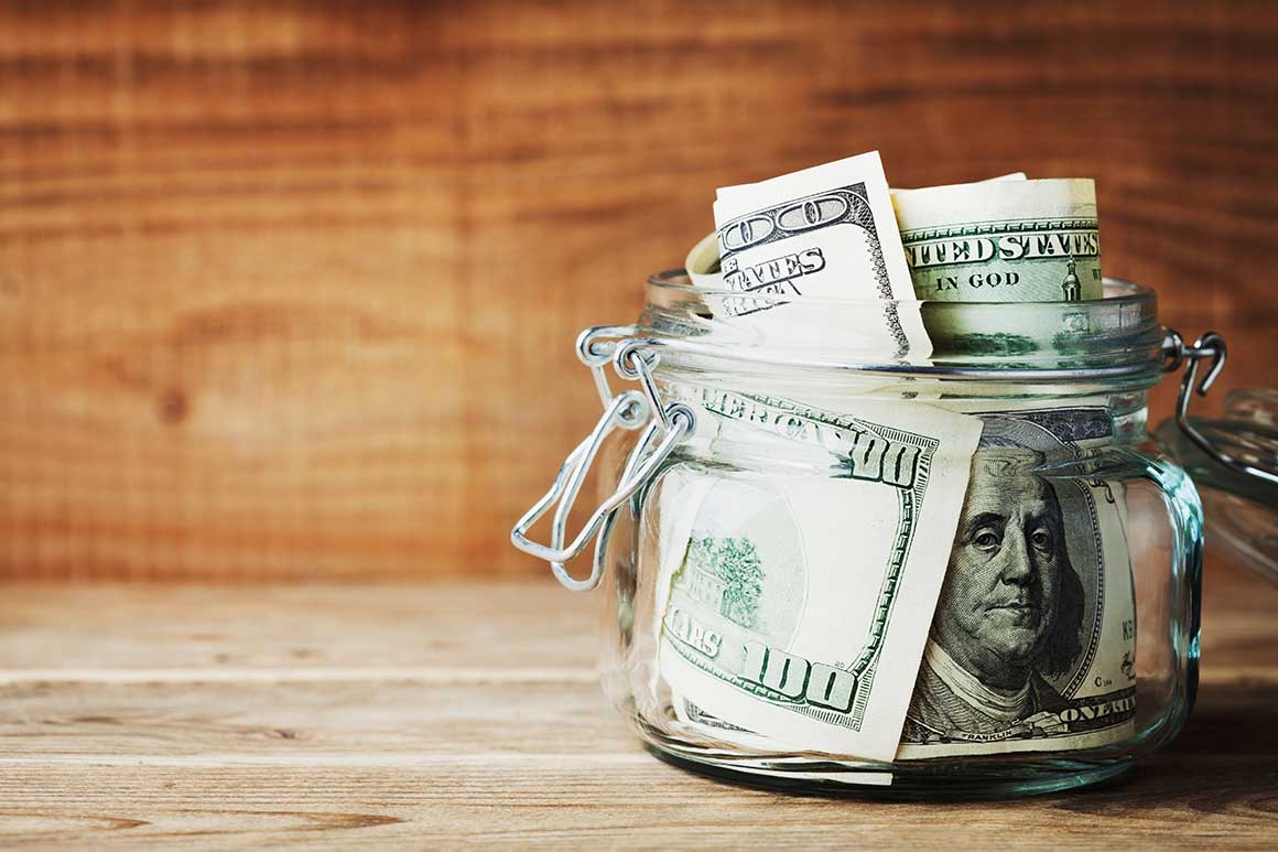 Hundred dollar bills in a glass jar