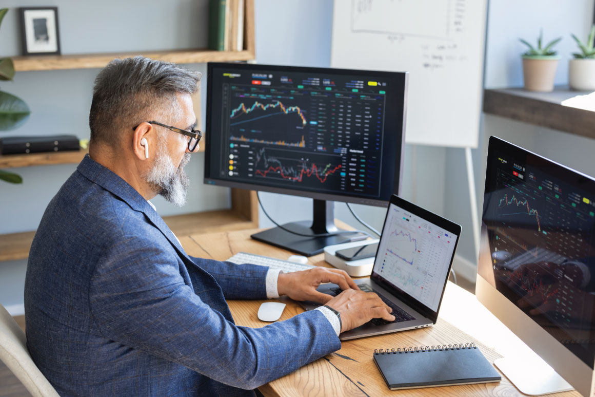 Man working at his desk with laptop and dual monitors