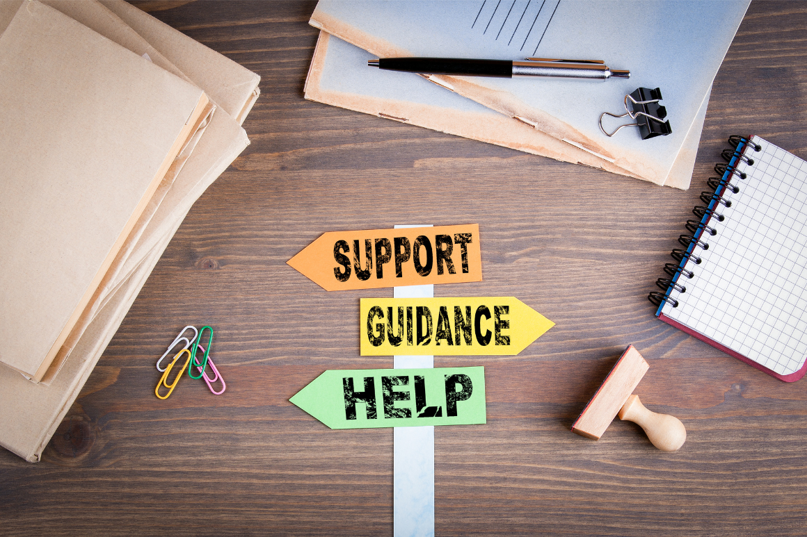 Support arrow, guidance arrow, and help arrow on a desk with notebook and file folders.