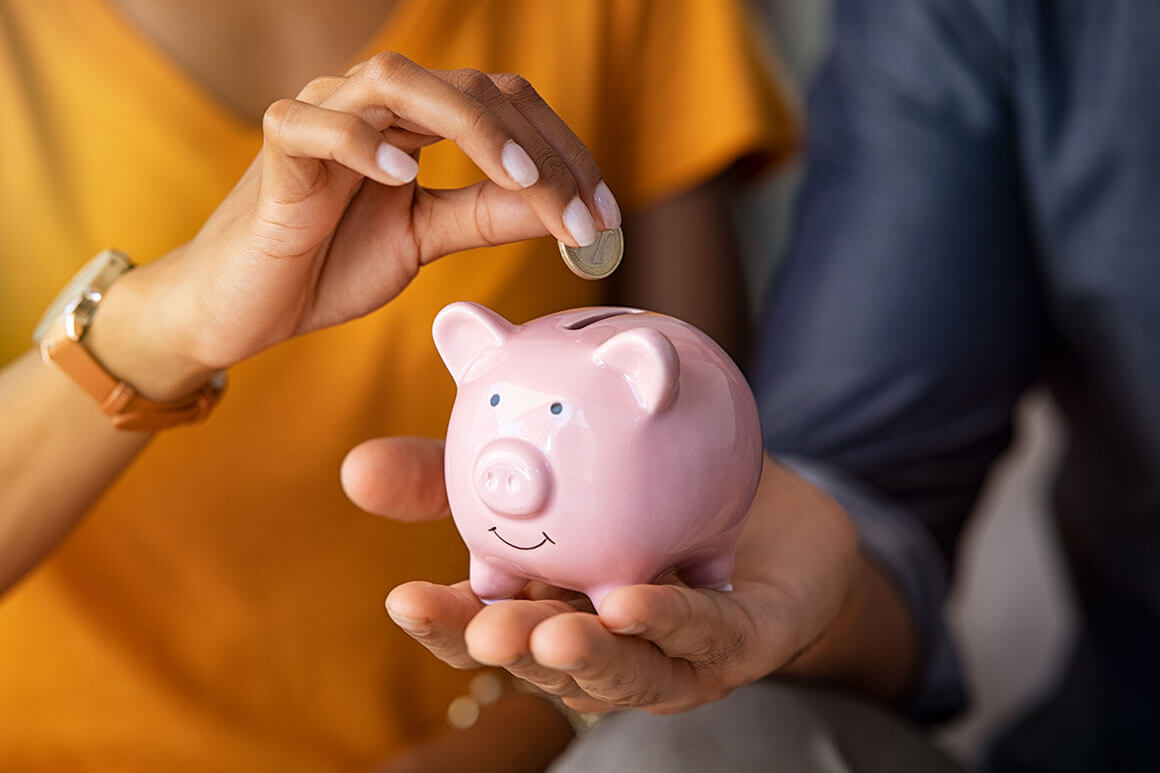Hand putting coin in a pink piggy bank