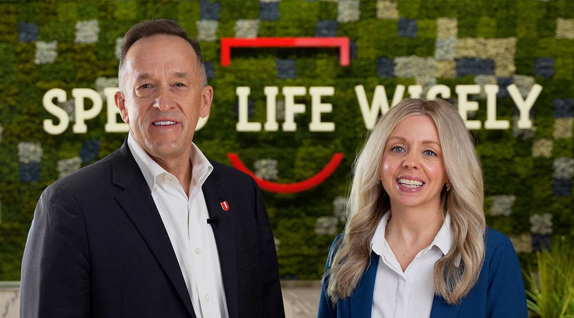 Greg Massey and Melissa Perrin in front of Spend Life Wisely wall