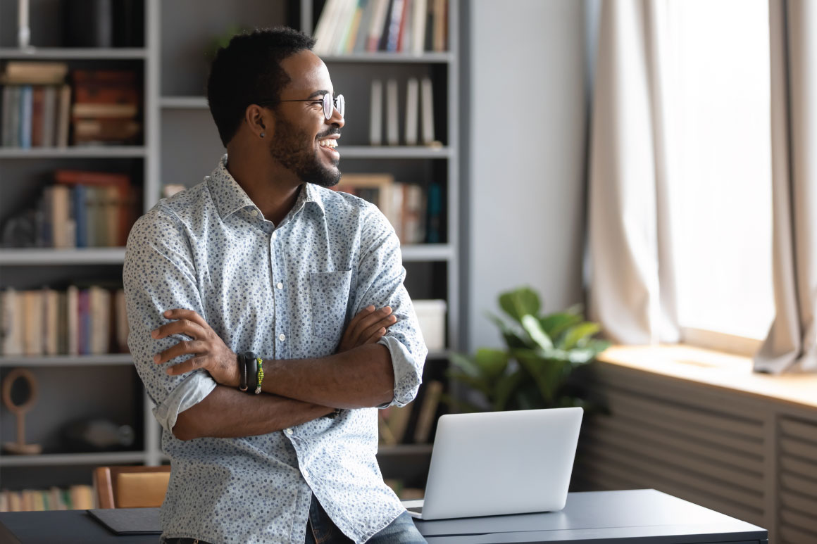 Happy man sitting on his desk and looking out the window