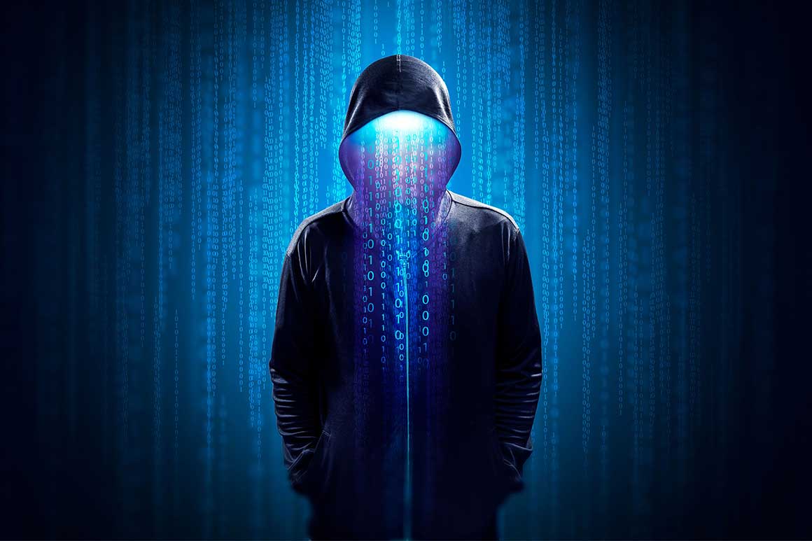 Against a dark backdrop of lines of blue binary code, a person in a black hoodie stands with their hands in their pockets, with more binary code emitting from under the hood of the hoodie.