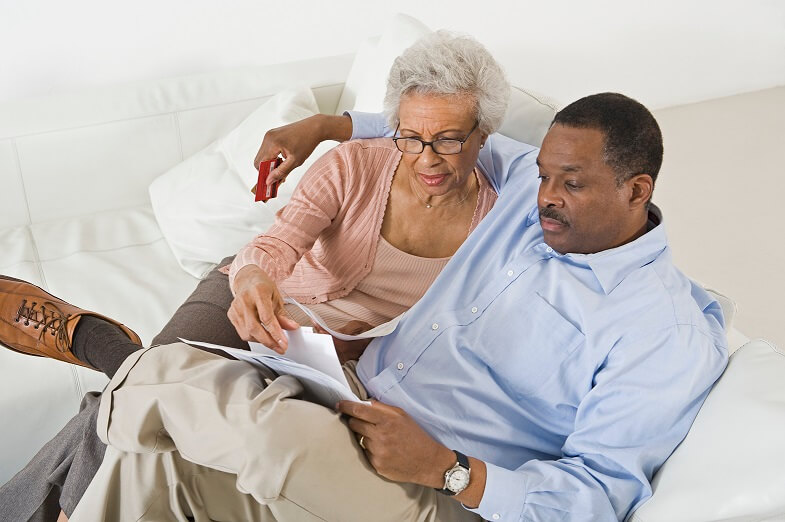 Senior couple sitting on a couch looking at their finances