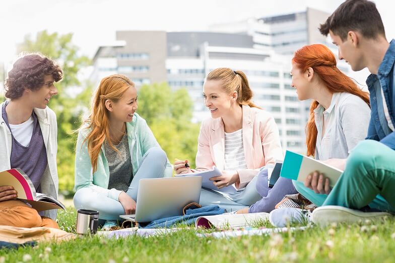5 people sitting on the grass socializing