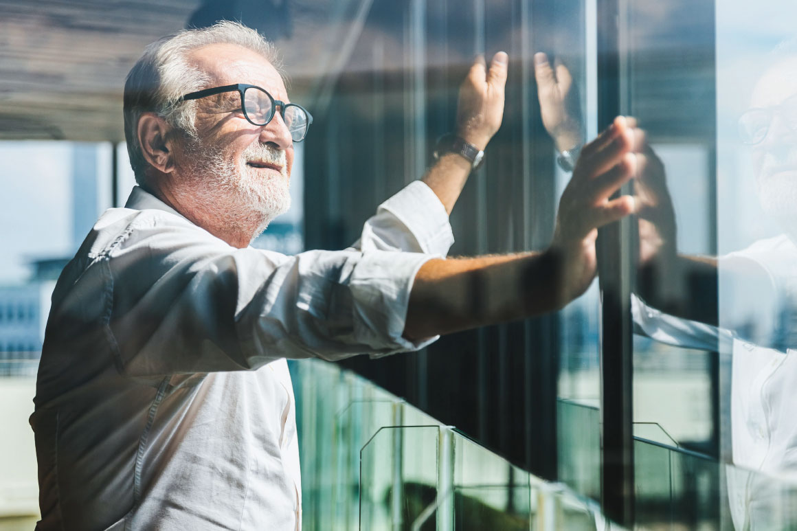 Older gentleman with hands on glass window 