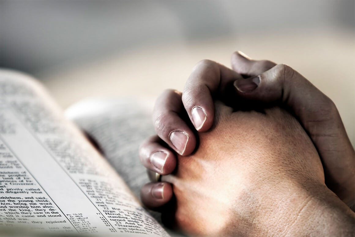 Praying hands on the Bible