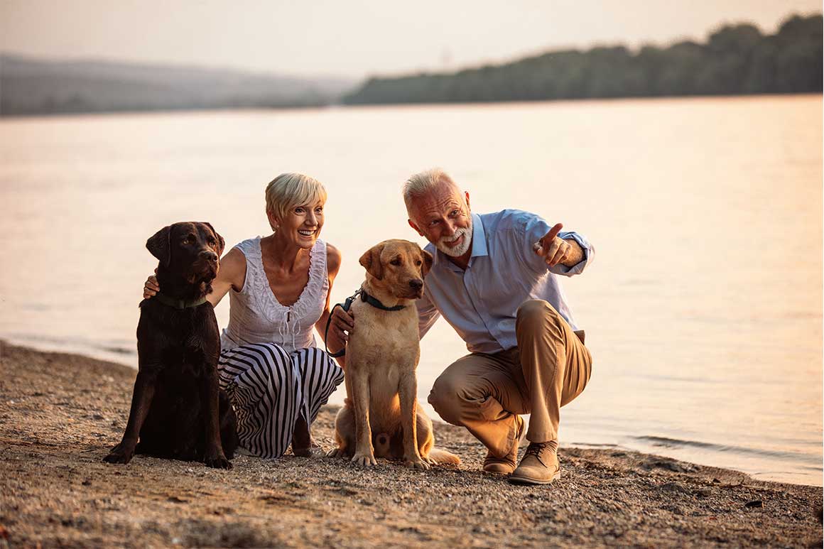 Elderly couple with their dogs at a lake.