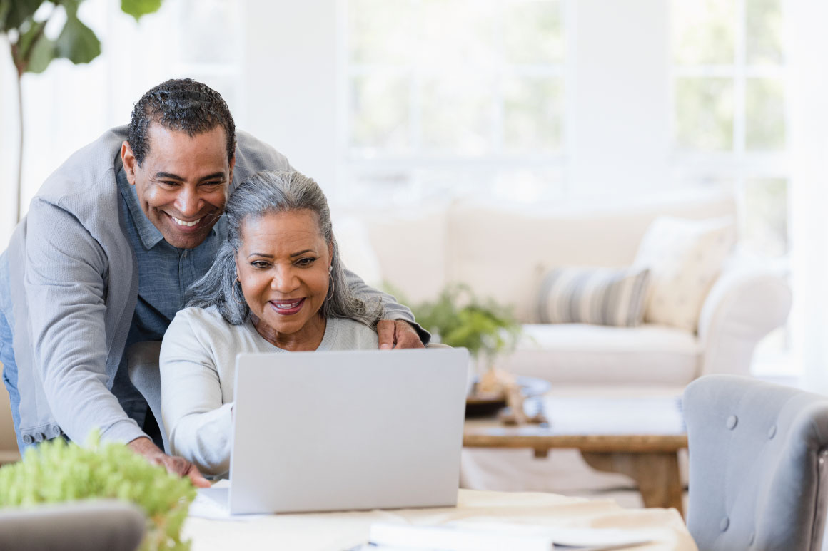 Couple smiling and looking at their retirement on their laptop