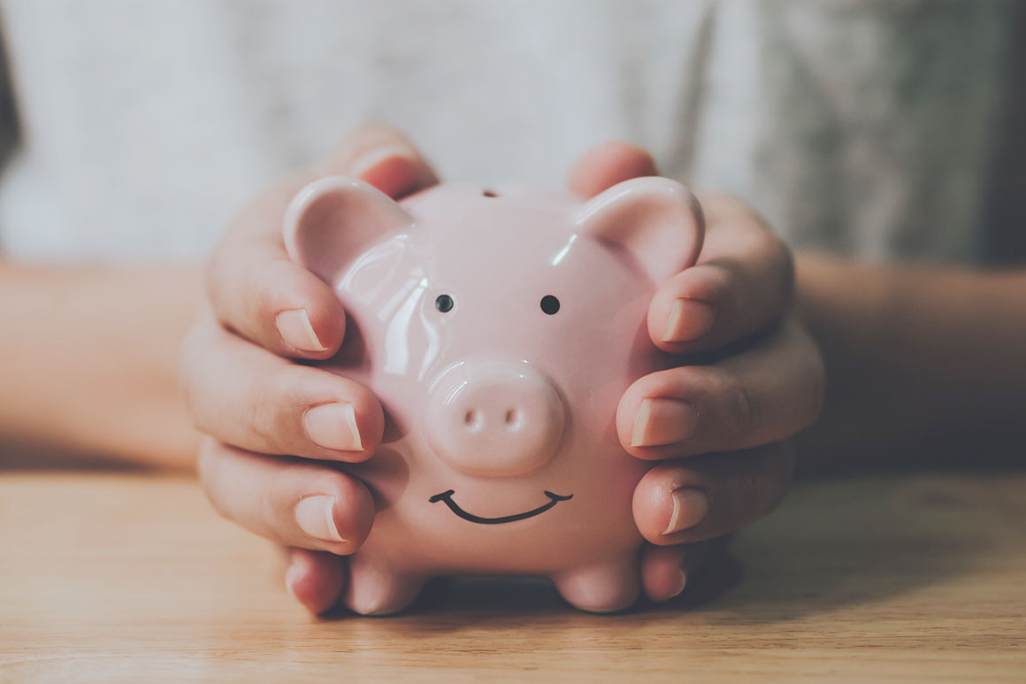 Hand holding pink piggy bank