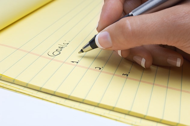 Pen on yellow notepads with goals written on it