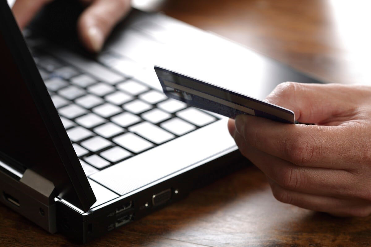 Hand holding credit card and typing on laptop