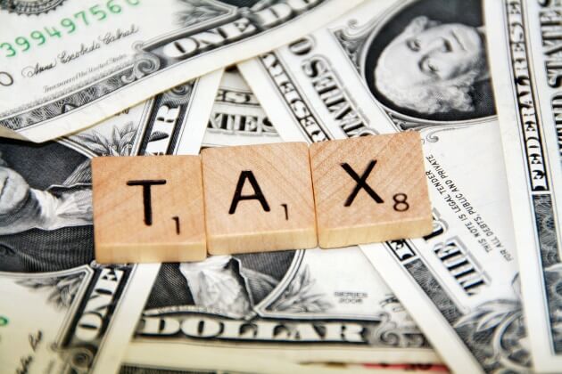 scrabble pieces spelling tax on top of dollar bills