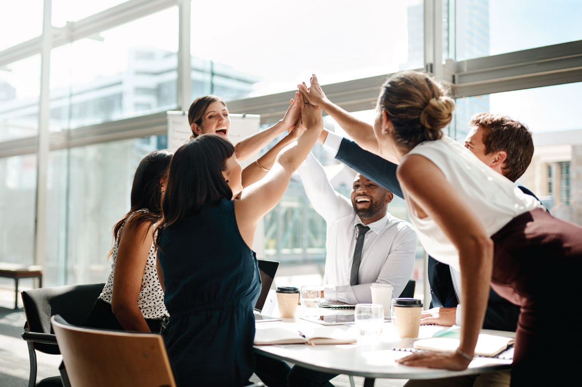 Coworkers and colleagues doing a group high five.